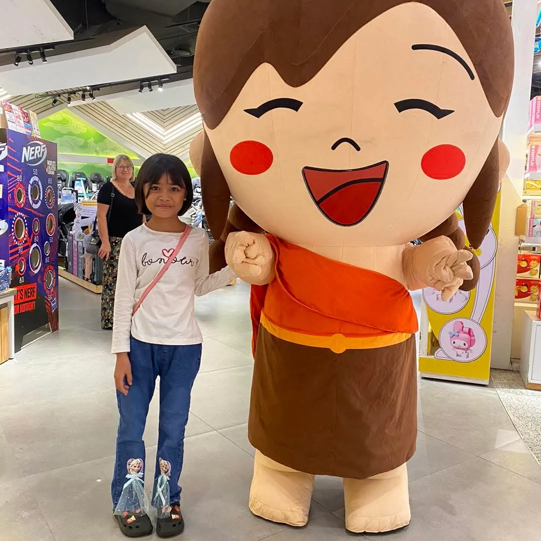Ngaih No dans un magasin de jouets à Bangkok, à côté d'une mascotte géante