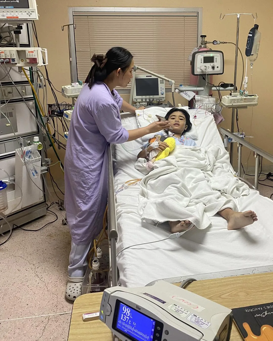 Ngaih No en soins intensifs à Bangkok, une infirmière à son chevet et une poupée posée près d'elle