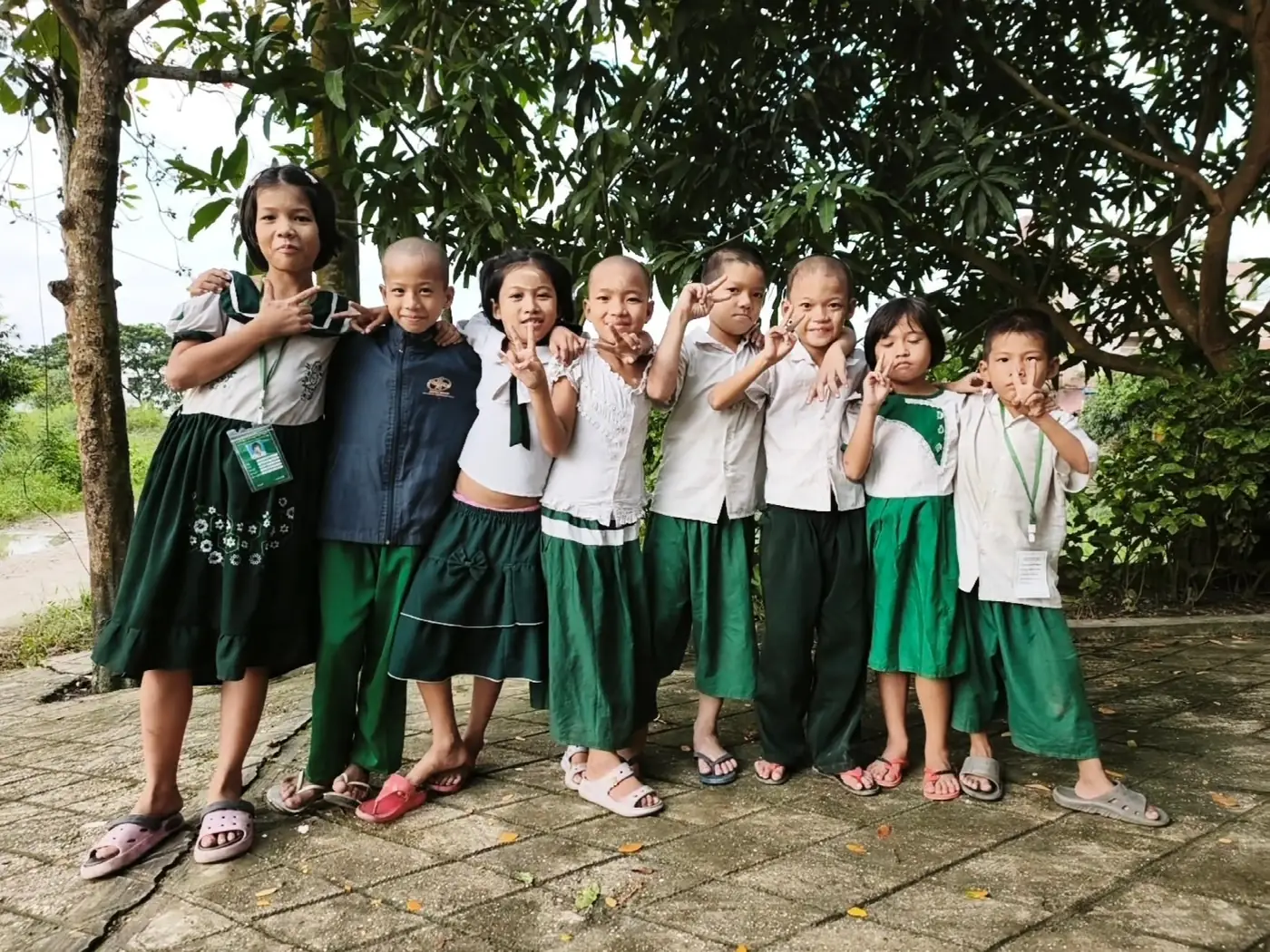 The nine Drop-In Center children arm in arm, in uniform, school badges round their necks