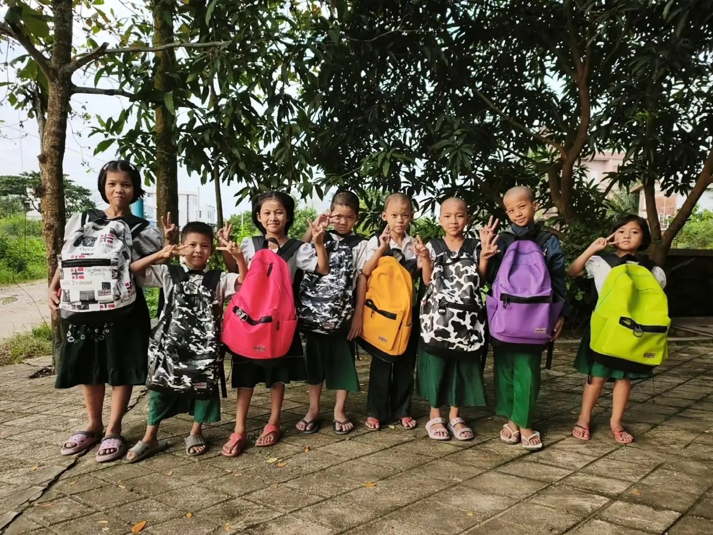 The Drop-In Center children with their new school bags, lined up under a tree
