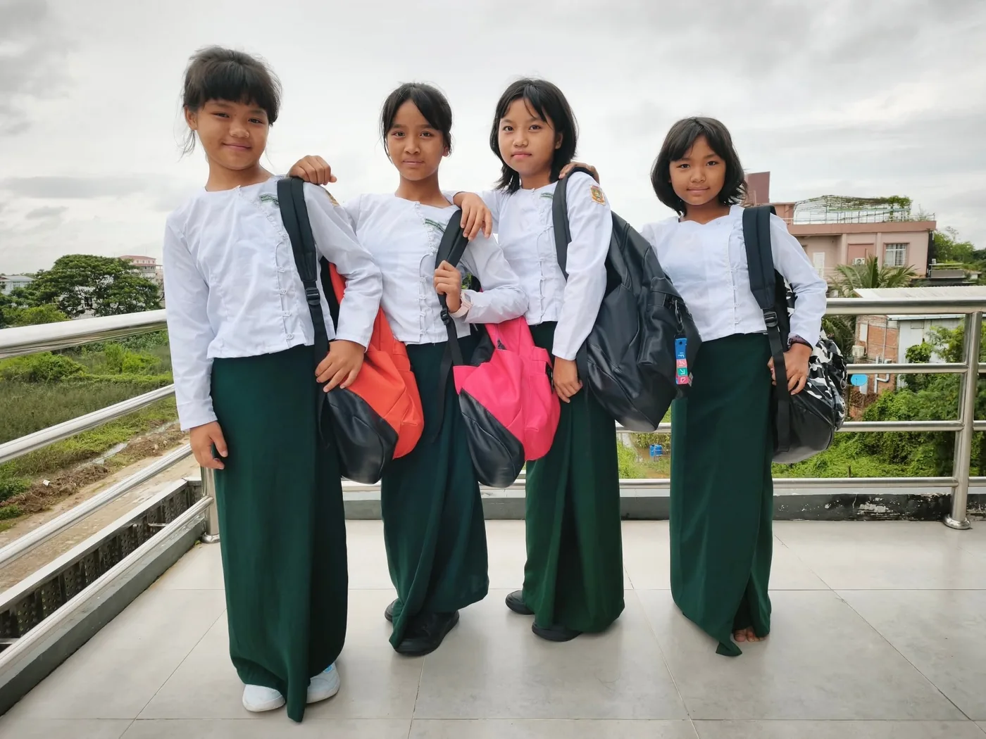 Four of the youngest girls at the boarding house, in uniform, bags on their shoulders