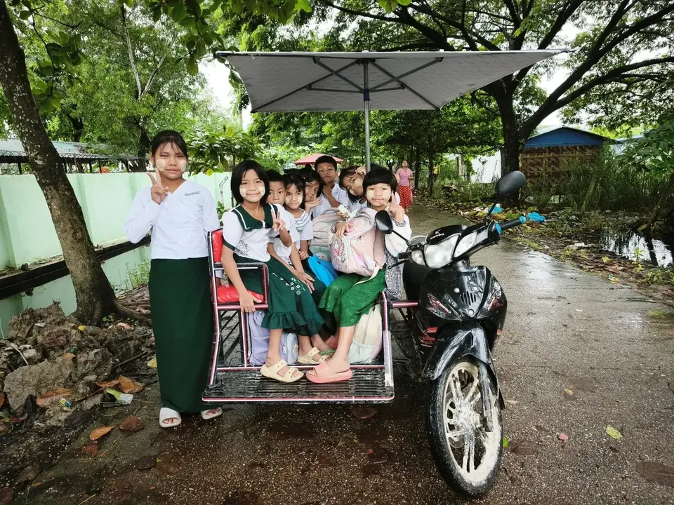 Des enfants sur le chemin de l'école, à moto, sous la pluie
